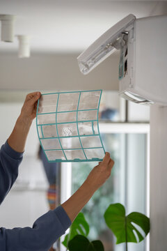 Closeup of woman removing dirty dusty air conditioner coarse filter for washing, cleaning. Home air conditioner service maintenance, repair and clean equipment. Dust cause of malfunction and illness