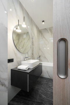 Faucet with ceramic sink and round mirror in the bathroom