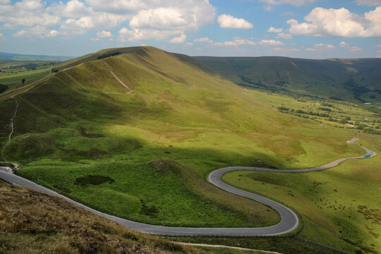 Scenic view of a winding asphalt road through green rolling hills in Edale Peak District
