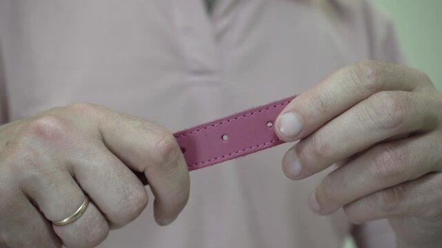 Close-up of hands showing handmade leather dog collar, Artisan demonstrating pink  leather pet collar with metal buckle