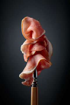 Raw fresh smoked pork bacon slices on a fork.