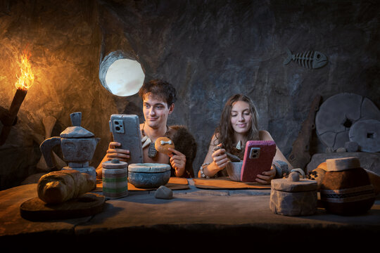 Prehistoric Couple Using Smartphones at Breakfast