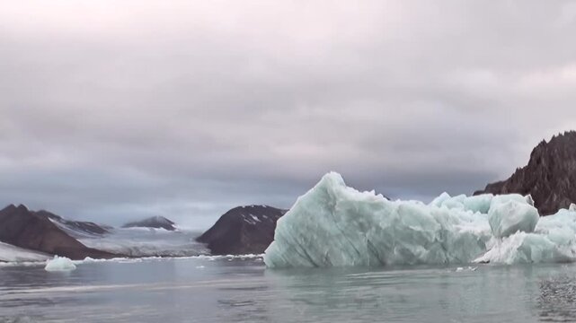 Witness massive icebergs gracefully floating in frigid Arctic Ocean. Majestic glacial formations and rugged mountains define this breathtaking polar wilderness on overcast day, hinting extreme travel.