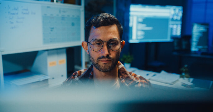 Young Caucasian male programmer write code on computer in home office at late night. AI technology, cybersecurity, software developer, freelance innovation, database system, digital network concept.