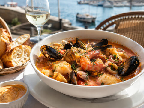  Bouillabaisse francesa con pescado fresco, gambas, mejillones y almejas, servida junto al mar con pan tostado.