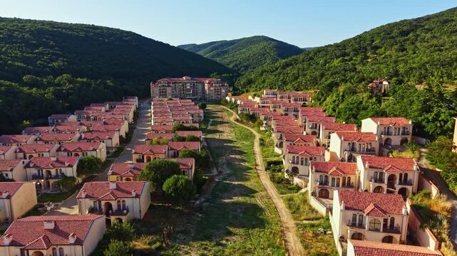 Elenite is seen after a flood. Many buildings are abandoned, and streets are empty. The landscape shows mountains in the background and green areas around the structures.