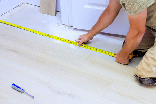 Worker carefully measures floor while preparing for flooring installation in house renovating