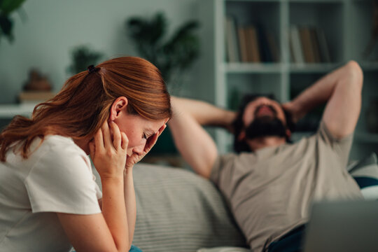 Couple having relationship problems at home, woman crying, man showing indifference and boredom
