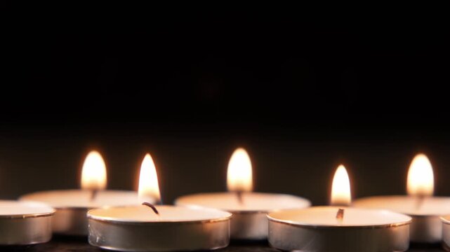 Candles burning in the dark at a gathering held indoors during the evening hours