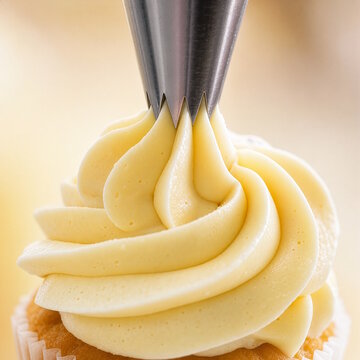 Piping star tip swirling buttercream frosting on cupcake, concept of baking and cake decoration