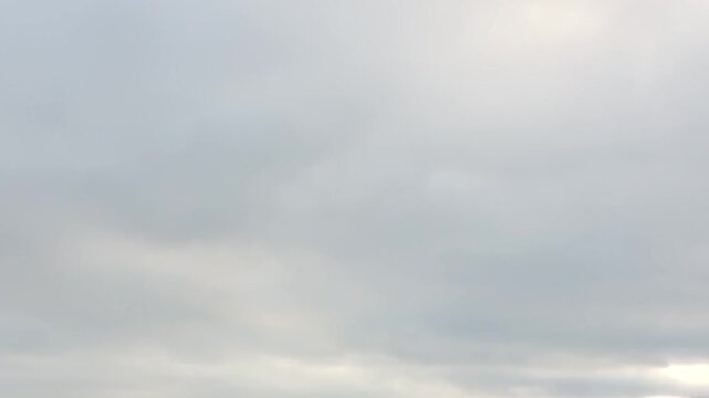 A boundless grey sky, thick with soft clouds, stretches infinitely above the serene Arctic waters of Svalbard, Norway.