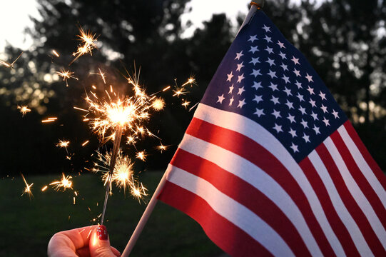 Holding sparklers with an American Flag to celebrate patriotic holiday - the 4th of July USA Independence Day