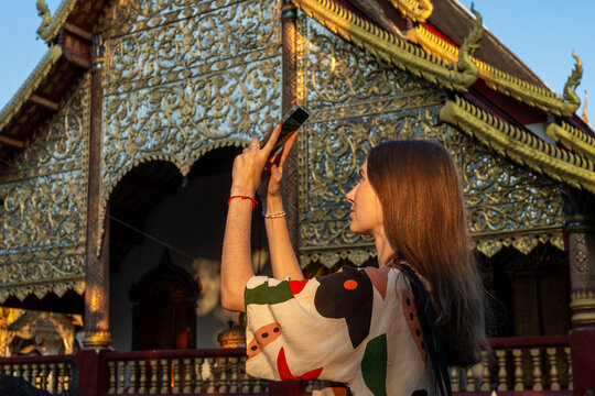 Woman Taking Photo in Front of Ornate Temple in Bright Sunlight