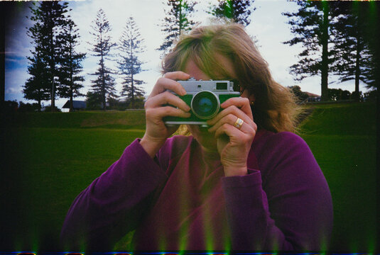 Woman Holds a Vintage Film Camera and Takes a Picture