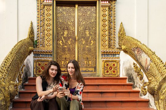 Two Friends Sitting on Steps at a Temple in Thailand