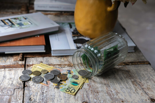 Australian cash notes and coins tipped out of a savings jar at home