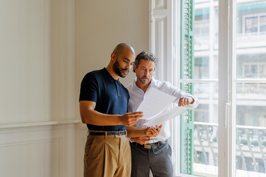 Interior designers discussing architectural plans in new property