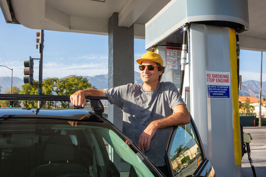 Man Standing in Door of Car at Gas Station
