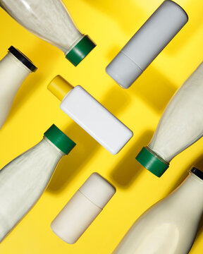 White plastic bottles floating over a yellow background