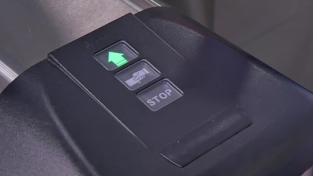 A person is seen tapping their card on a transit validator at a bustling city station. The lights flash as the card is accepted, enabling smooth passage for commuters during rush hour.