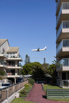 A plane flying low behind residential apartments
