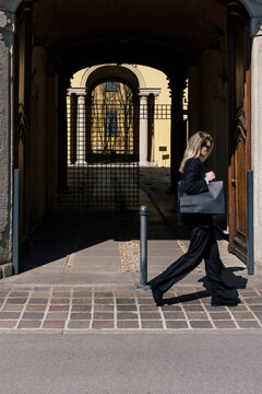 Woman in black outfit wallking with shopping bag