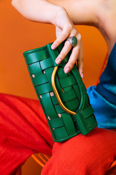 Woman holding vibrant green woven clutch bag