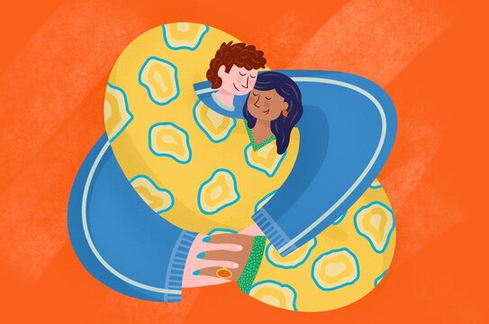 A man and woman hug in brightly coloured clothes.