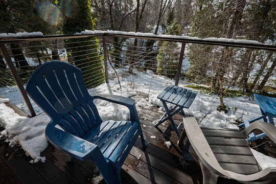 Plastic chairs sit on a snow-dusted wooden deck