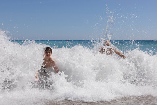 A boy and his father are playing in the waves