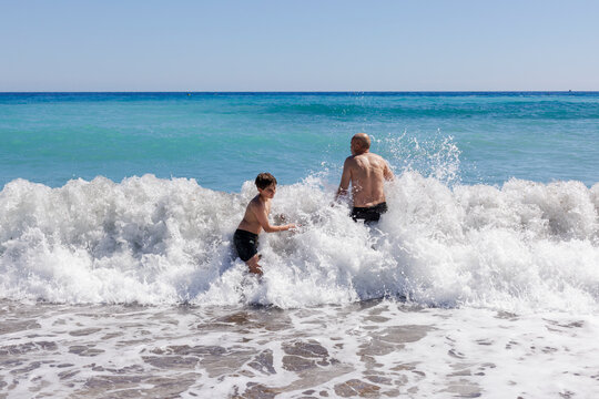 A boy and his father are playing in the waves