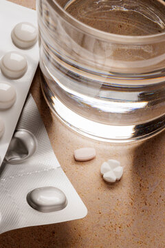 Pill strips with two separate pills next to a glass of water
