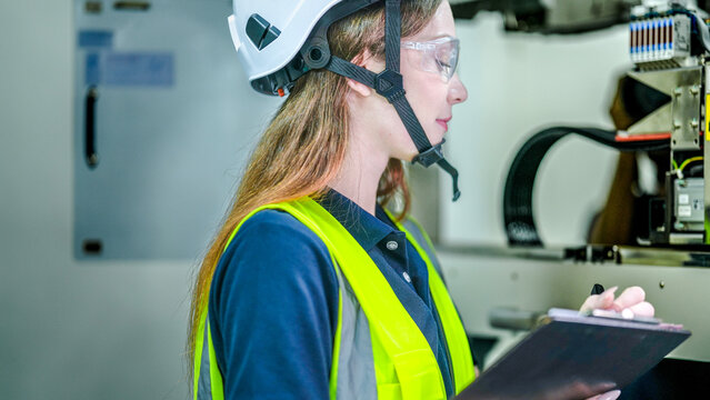 A female robotics engineer in an R and D lab. She is focused, concentrating on programming an AI driven robot or microchip manufacturing system.