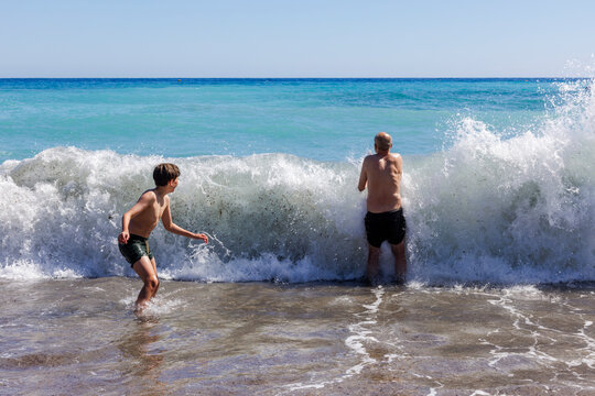 A boy and his father are playing in the waves