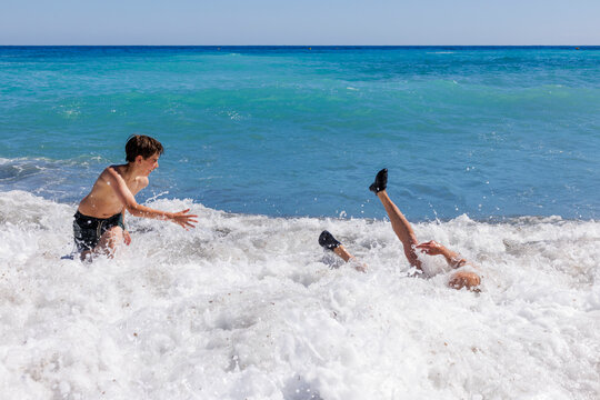 A boy and his father are playing in the waves