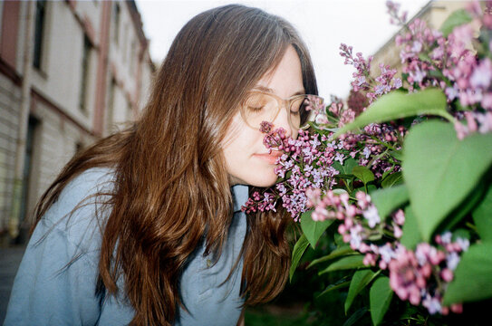 Woman enjoys the smell of flowers in a city street during daytime