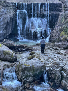 Weiblicher Wanderer steht an einem kleinen Wasserfall an der Wei&szlig;en Achen im Chiemgau, Alpen, Bayern, Deutschland