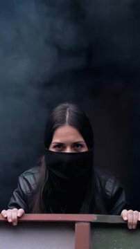 Woman partially obscured by dense smoke or fog peering over a railing