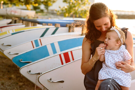 mom holding baby by boats
