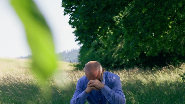 Man sitting in a field, deep in thought or meditation, symbolizing mental health, stress relief, and finding inner peace in nature.