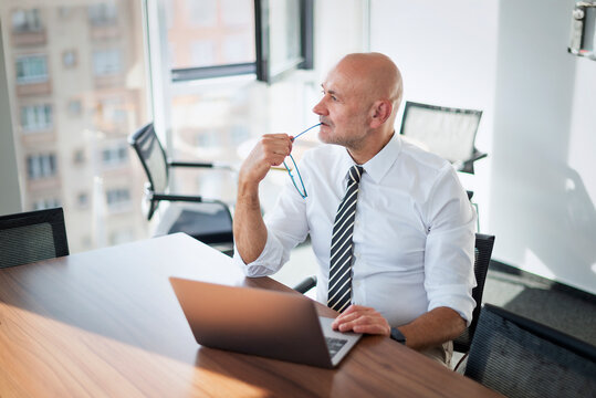 Thoughtful businessman working on laptop in meeting room