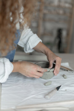 Woman potter meticulously shaping clay in a studio setting
