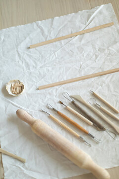 Creative clay pot on worktable with wooden handles and cloth, top-down