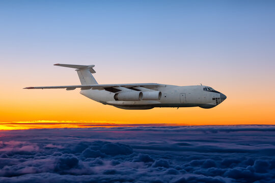 White wide body transport freight airplane flying above the cumulus sunrise sky