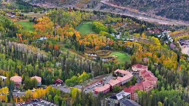 Aerial view of condos, homes, and golf course in Mountain Village ski town of Telluride, Colorado landscapes with fall foliage trees during autumn season colors in San Juan Mountains - 4K Drone