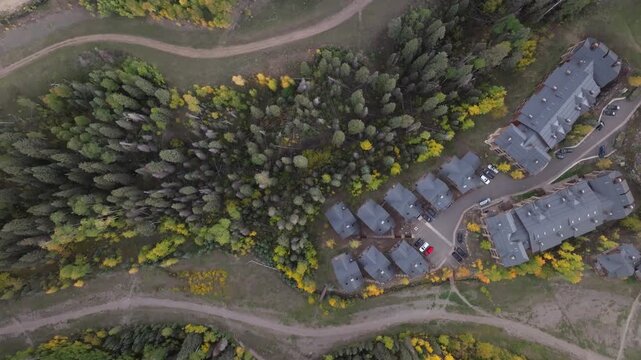 Bird's eye aerial view of condos, homes, and golf course in Mountain Village ski town of Telluride, Colorado landscapes with fall foliage trees during autumn season in San Juan Mountains - 4K Drone