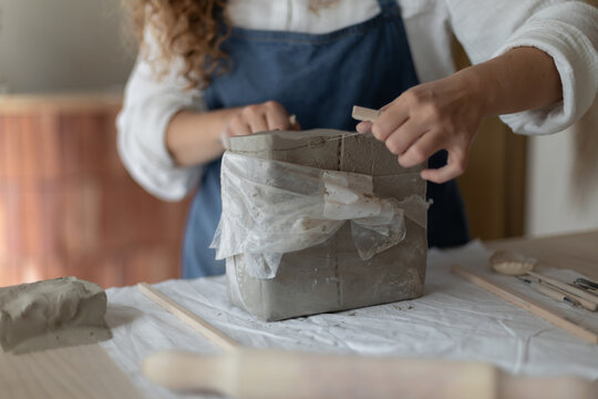 A pottery shaping clay in a studio setting with a person in an apron