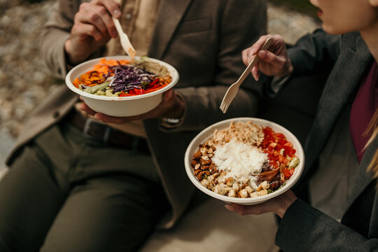 People eating fresh healthy salads in compostable bowls