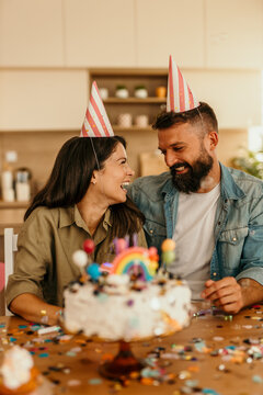 Happy couple celebrating birthday with cake and confetti at home