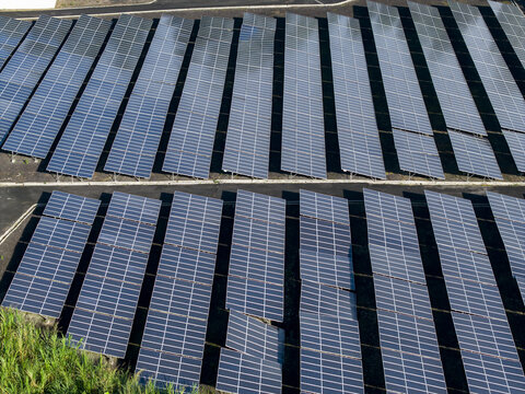 Aerial view of the PLTS 1MWp Bangli solar farm, featuring rows of photovoltaic panels arranged in a grid pattern across the landscape in Bangli, Bali, Indonesia.